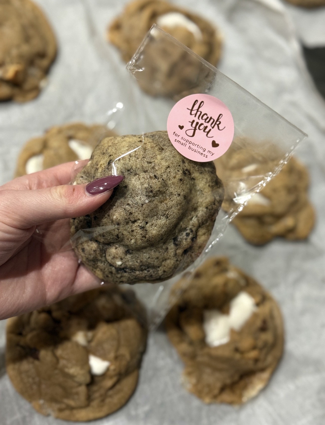 Hand holding a cookies and cream cookie in a bag with a thank-you sticker